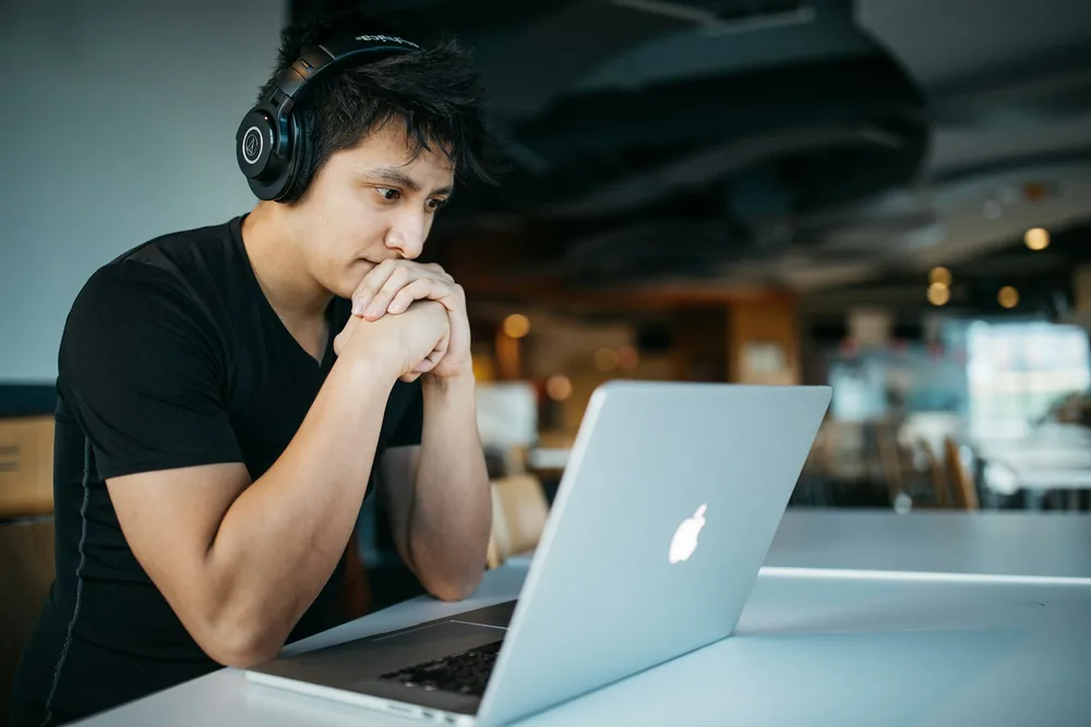 A learner wearing headphones and studying at a laptop